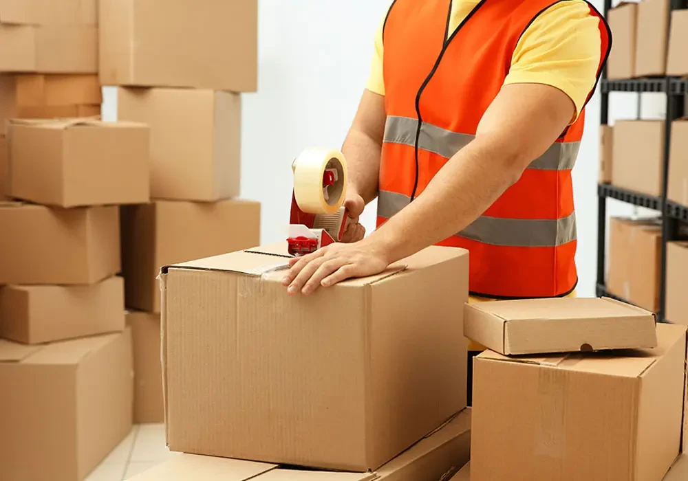 ICL worker sealing and packing a cardboard box for shipment